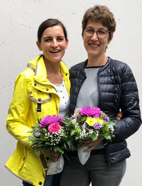 Zwei Mitarbeiterinnen mit Blumensträußen